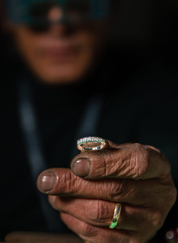 gioielli artigianali personalizzati, anello creato su misura con diamanti tra le mani sporche dell'artigiano che ha finito di lavorare il metallo